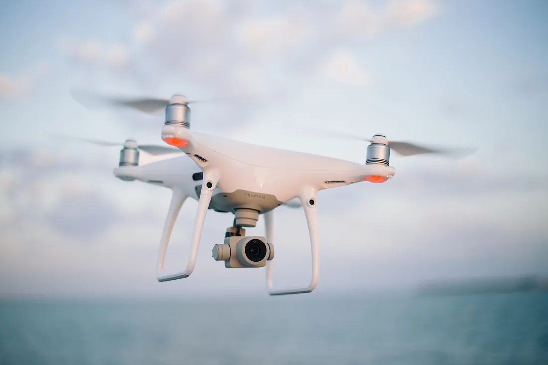 White quadcopter camera drone in flight.
